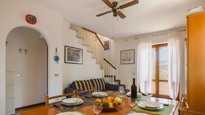 A dining area with a wooden table set for four, a sofa, and a staircase leading to an upper floor. - Casa Claudia by Interhome (Lido di Camaiore)