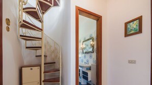 A spiral staircase with a wooden finish and a small cabinet at the bottom. - Casa Claudia by Interhome (Lido di Camaiore)