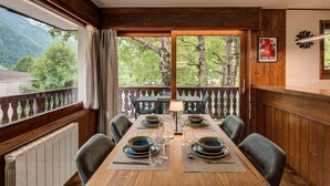 A dining area with a wooden table set for six, a view of the outdoors, and a sign on the wall.