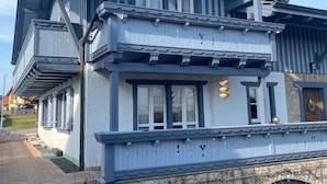 Een gebouw met twee verdiepingen, een balkon, grote garage deuren en een stenen fundering.