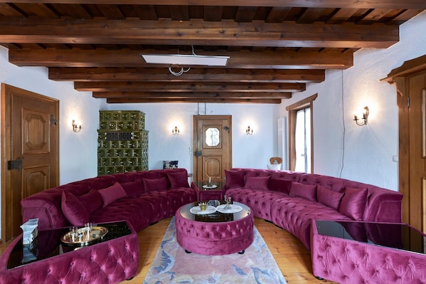 Une pièce comprenant un grand canapé d’angle, un pouf rond et une table basse en verre.