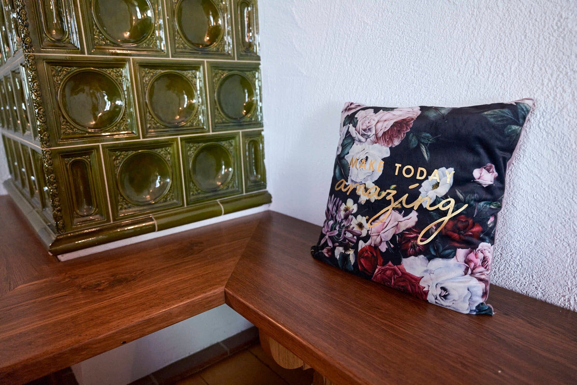 A wooden bench with a floral pillow and a decorative glass cabinet.