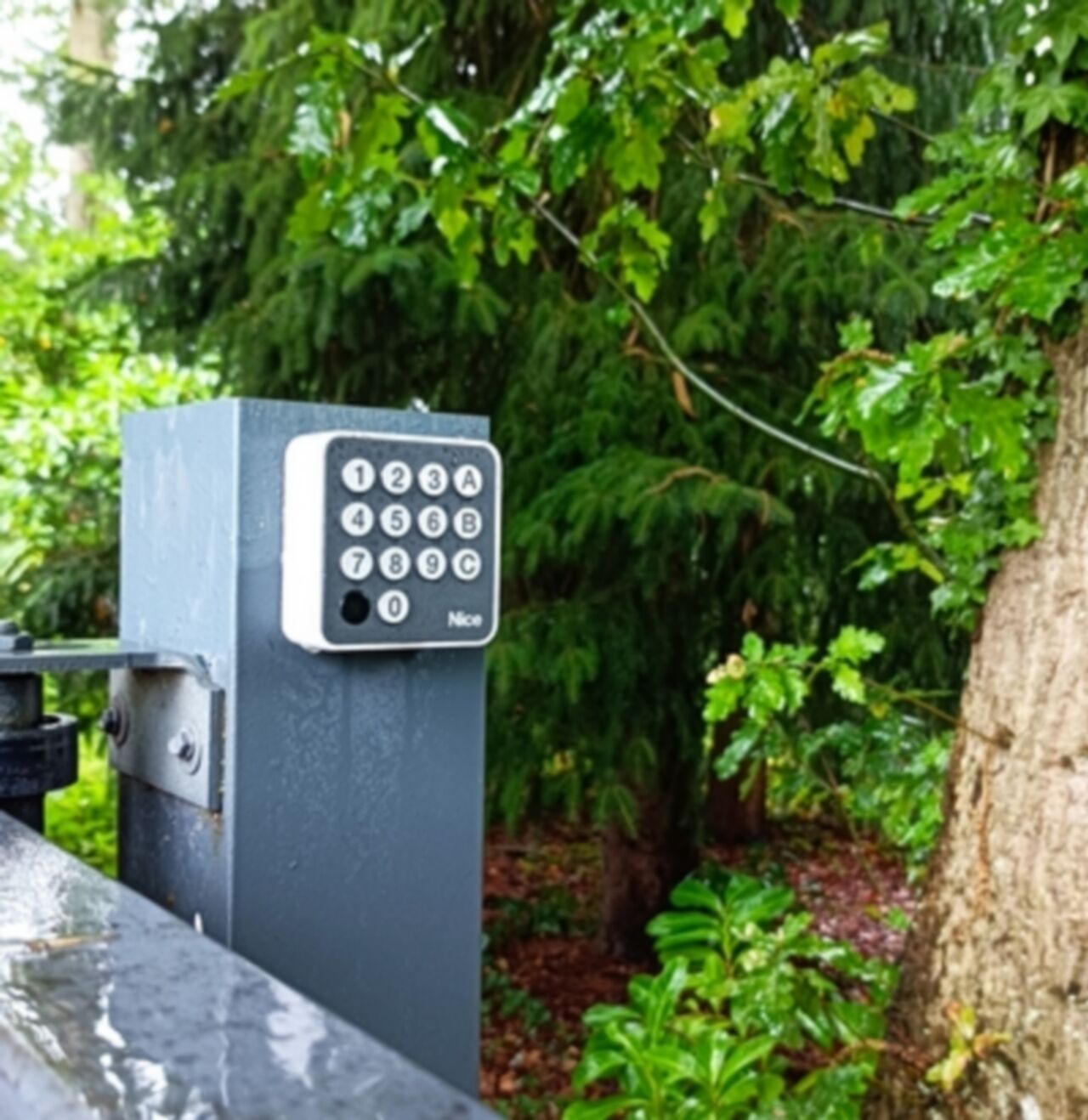 A keypad security device, likely for a garage or entrance, surrounded by lush greenery.