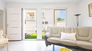 Un salon comprenant un canapé, une table basse et une porte donnant sur un espace extérieur.