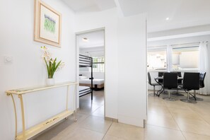 A modern interior with a dining area, a bed, and a staircase leading to another room.
