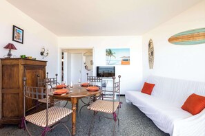 Uma área de refeições com mesa de madeira, cadeiras e sofá branco.