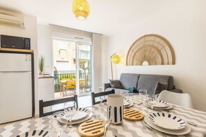 Comedor con una mesa dispuesta para cuatro personas, microondas, refrigerador y vistas al exterior.