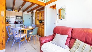 A cozy interior with a dining area, kitchen, and a red leather sofa. - La Parenthese au Sud · Valras'Loc (Valras-Plage)