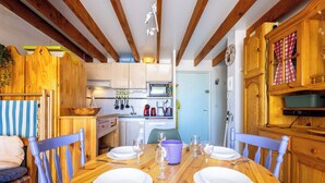 A wooden dining table set with plates, glasses, and cutlery, surrounded by blue chairs. - La Parenthese au Sud · Valras'Loc (Valras-Plage)