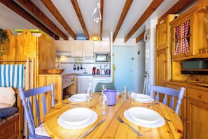 A wooden dining table set with plates, glasses, and cutlery, surrounded by blue chairs.
