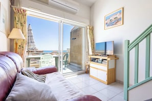 Un balcón con vistas al mar, un sofá, un mueble para televisión y una lámpara.