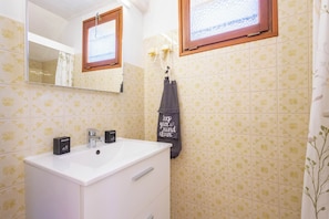 Une salle de bain avec un lavabo blanc, un miroir et un porte-serviettes sur lequel est posée une serviette.