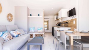 A modern living room with a sofa, coffee table, and a dining area with a table and chairs.