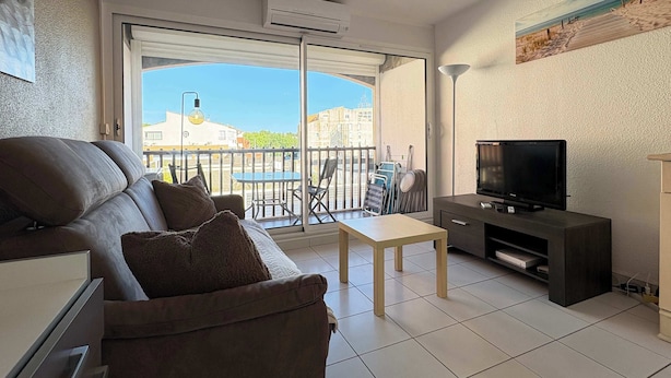 Un salon moderne avec un canapé, un téléviseur et un balcon offrant une vue sur la ville.