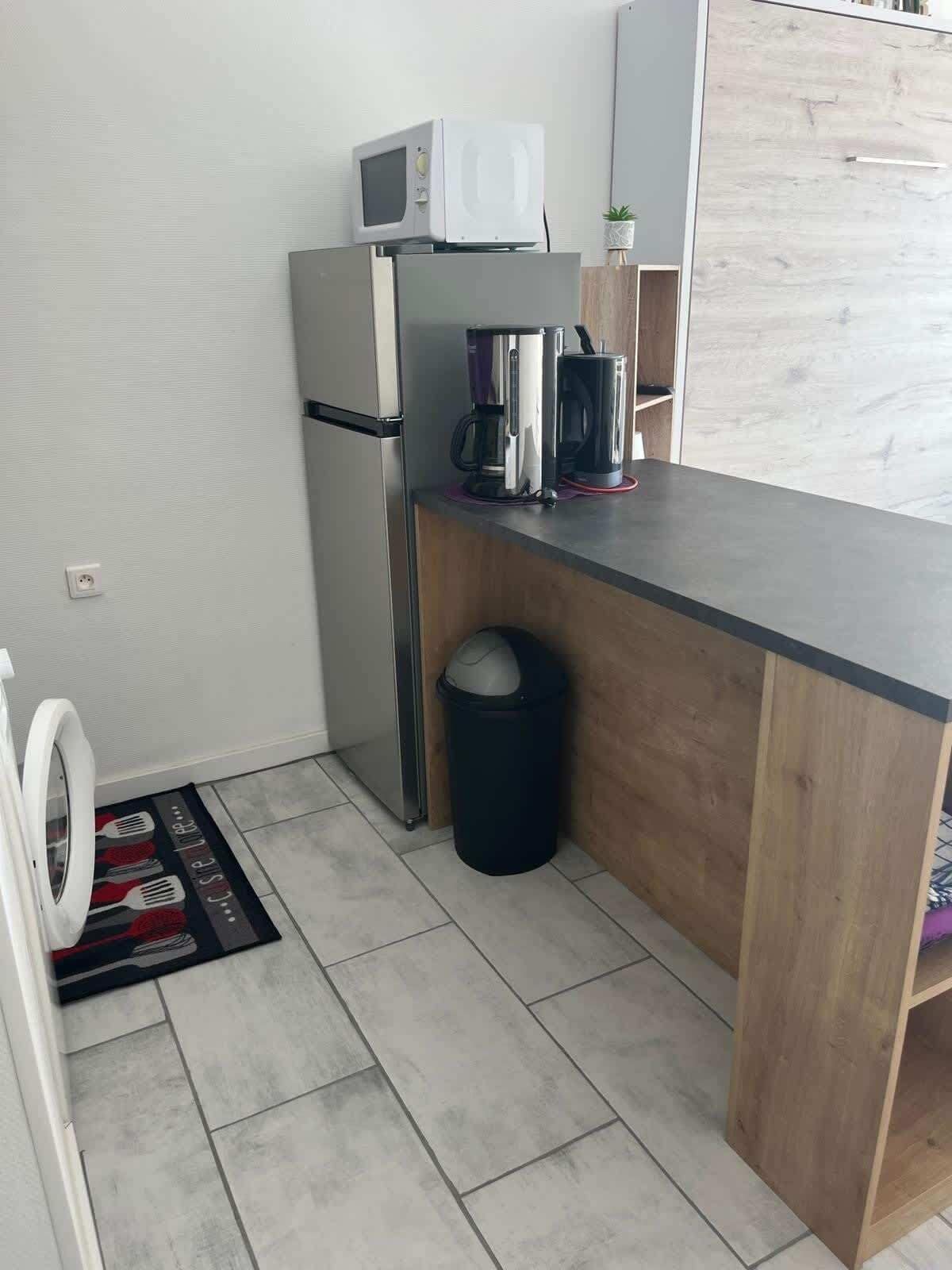 A compact kitchenette with a microwave, coffee maker, and a trash bin.