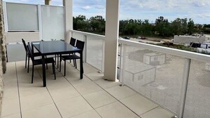 An outdoor patio with a table and chairs, a pergola, and a view of the surrounding area. - Loggia Verde – Charming studio 450 m from the sea (Sérignan)