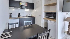 A compact kitchen with a dining area, a microwave, a coffee maker, and a dishwasher. - Loggia Verde – Charming studio 450 m from the sea (Sérignan)