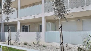 A multi-story building with balconies, a gated entrance, and a landscaped area with small trees. - Loggia Verde – Charming studio 450 m from the sea (Sérignan)