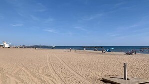 A wide sandy beach with a lifeguard tower and umbrellas in the distance. - Comfortable Studio with Harbour View (Valras-Plage)