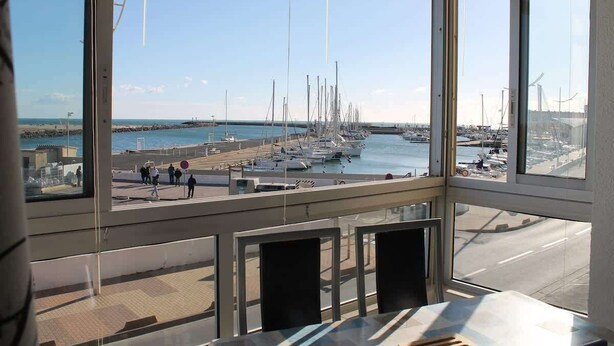 A view from a high-rise building overlooking a marina with boats and people. - Comfortable Studio with Harbour View (Valras-Plage)