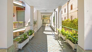 A narrow corridor with tiled flooring, potted plants, and a mural on the wall. - Strixia Apartment - 50m From Lake With Balcony (Stresa)