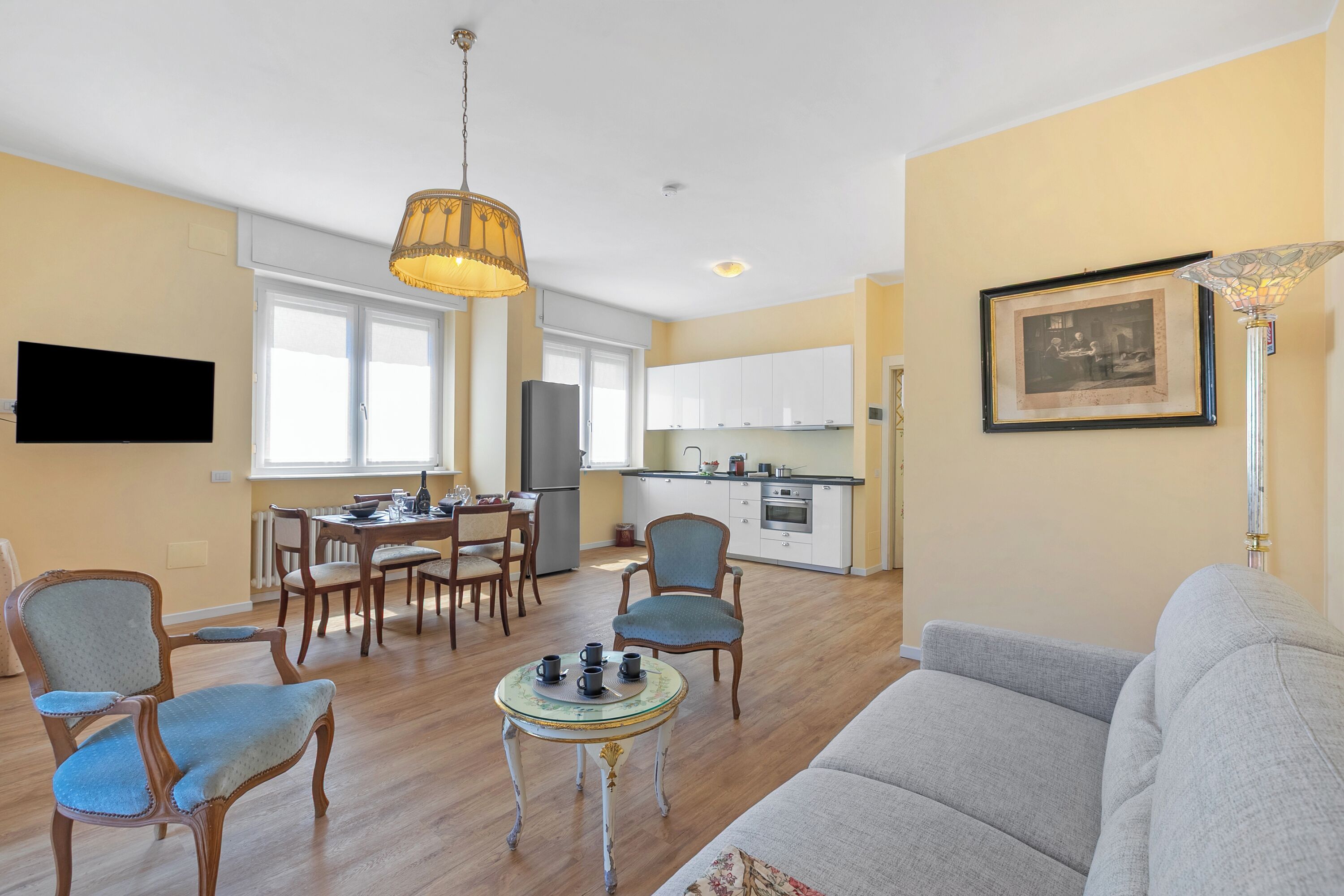 A living room with a sofa, chairs, a dining table, and a kitchen in the background.