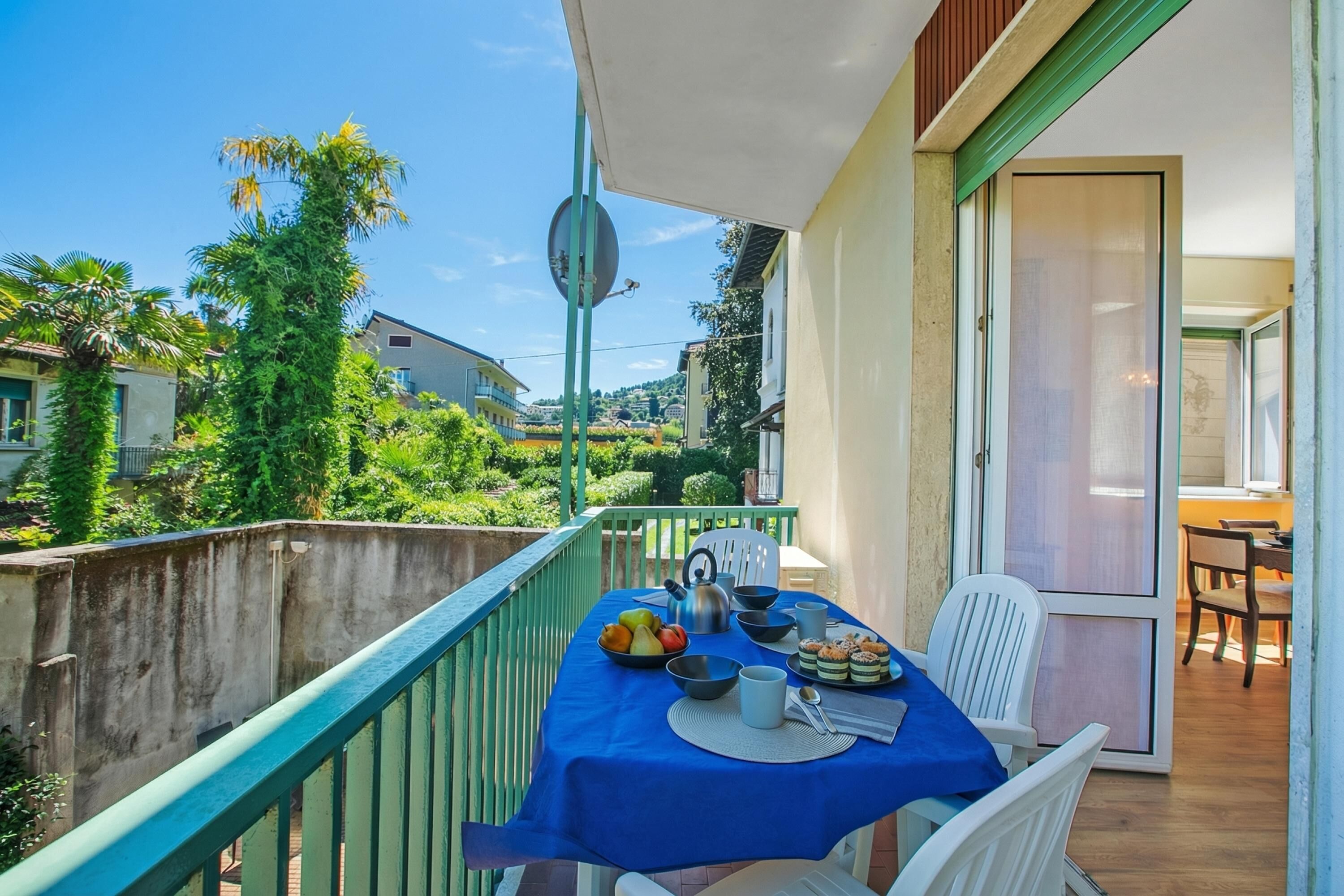 A balcony with a table set for dining, a satellite dish, and a view of a residential area.