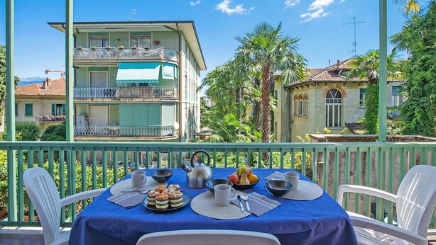 A balcony with a table set for breakfast, including fruits, pastries, and a kettle. - Strixia Apartment - 50m From Lake With Balcony (Stresa)