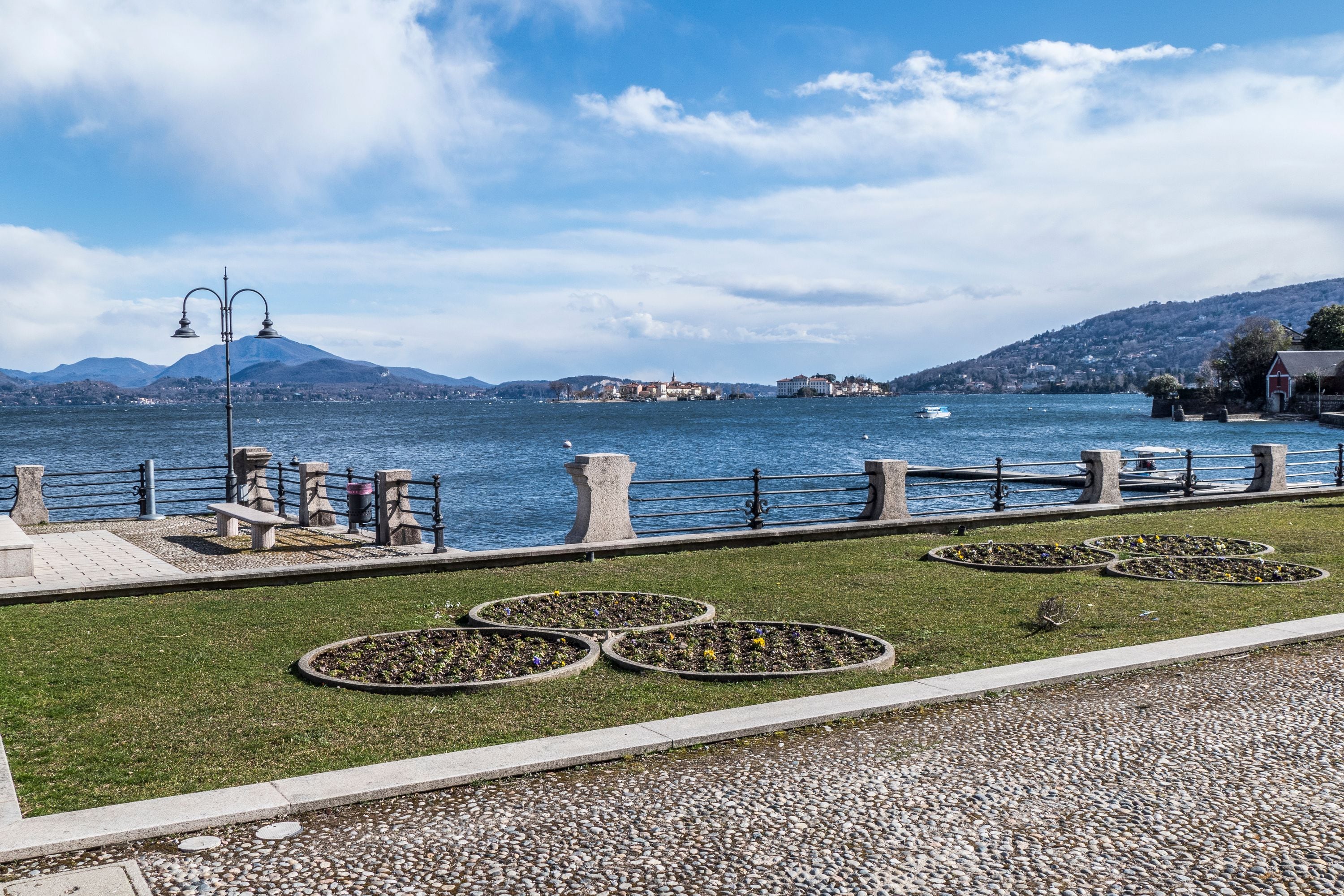 Une promenade en bord de mer agrémentée d’une balustrade en pierre, de bancs et de parterres de fleurs.