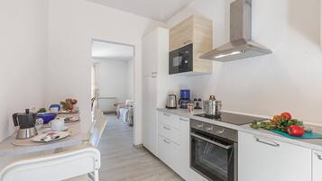 A modern kitchen with white cabinets, a built-in oven, a microwave, and a coffee maker.