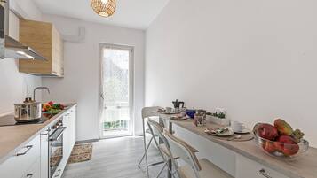 Une cuisine moderne avec des armoires blanches, un comptoir en bois et une grande fenêtre.