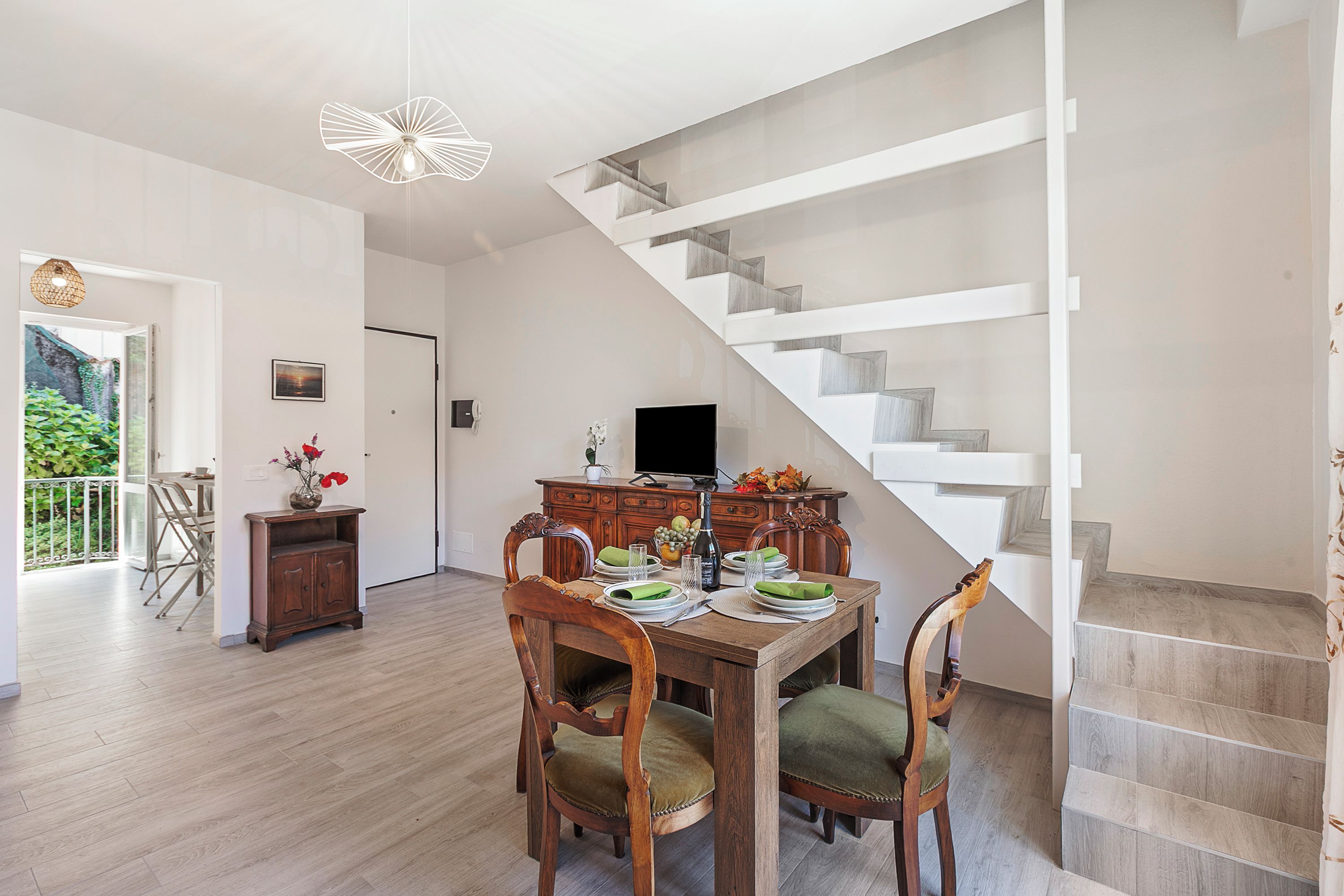 A dining area with a wooden table, chairs, and a staircase.