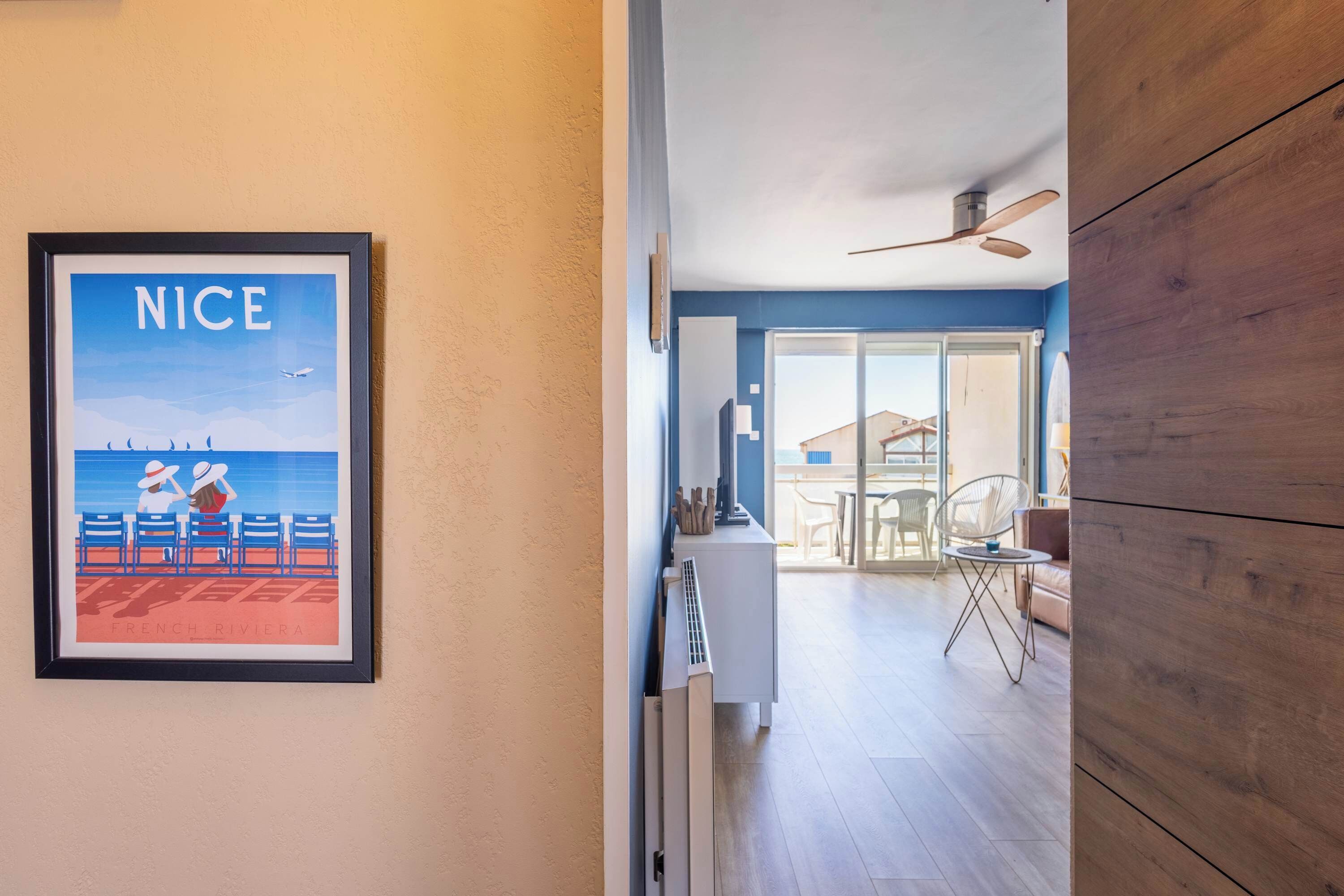 A hallway with a framed picture, a ceiling fan, and a view into a dining area with a table and chairs.