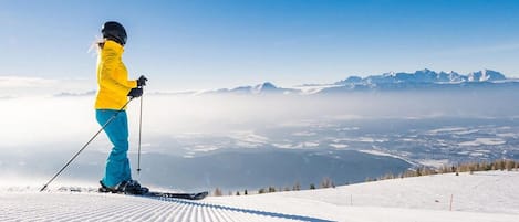 A person skiing on a snowy slope with a mountain range in the background.