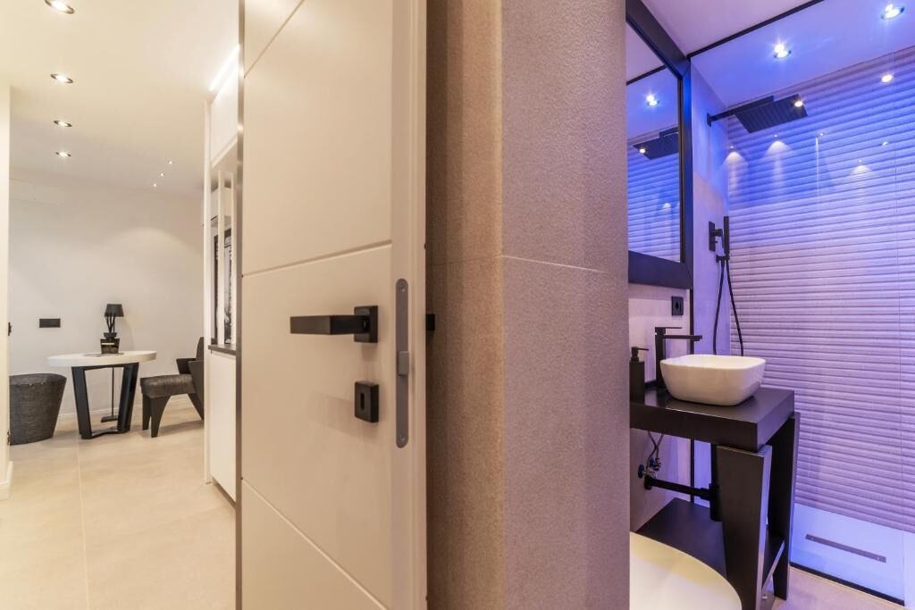 A modern bathroom with a large mirror, a white sink, and a towel rack.