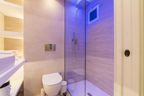 A modern bathroom with a glass-enclosed shower, a toilet, and a vanity with a mirror. - JOIVY Elegant Suites Near Villa Borghese (Rome)