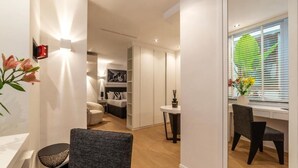 A modern interior with a dining area, a sofa, and a workspace with a window. - JOIVY Elegant Suites Near Villa Borghese (Rome)