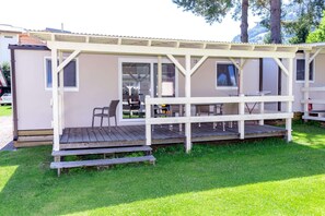A mobile home with a porch, outdoor seating, and a small deck.