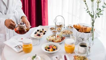 Una mesa con mantel blanco llena de una variedad de platos para el desayuno, como tostadas, fruta y bollería.