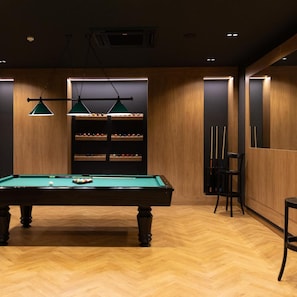 A billiards table with a green felt surface, surrounded by wooden walls and a herringbone floor pattern. - Venus Hotel Pristina (PRISTINA)