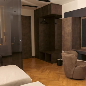 Un interior moderno con piso de madera en espiga, un sofá, una mesita y un televisor montado en la pared.
