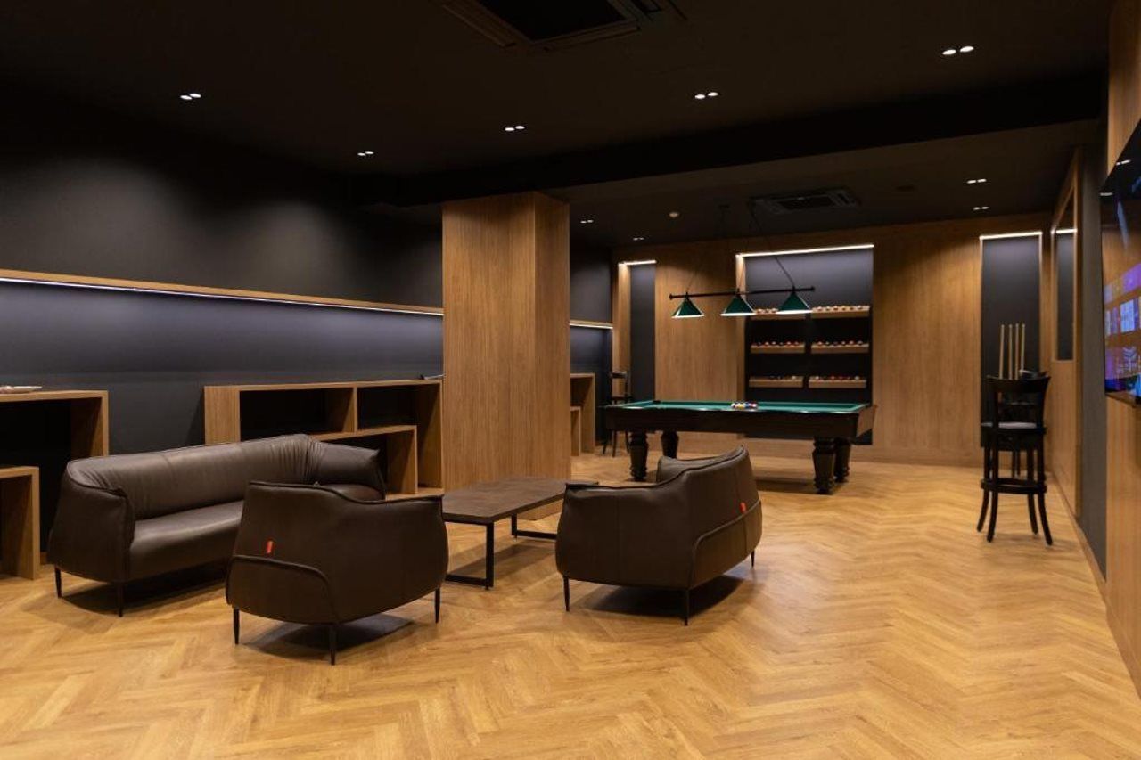 Une salle de billard équipée d’une table de billard, de canapés en cuir et d’un coin bar.
