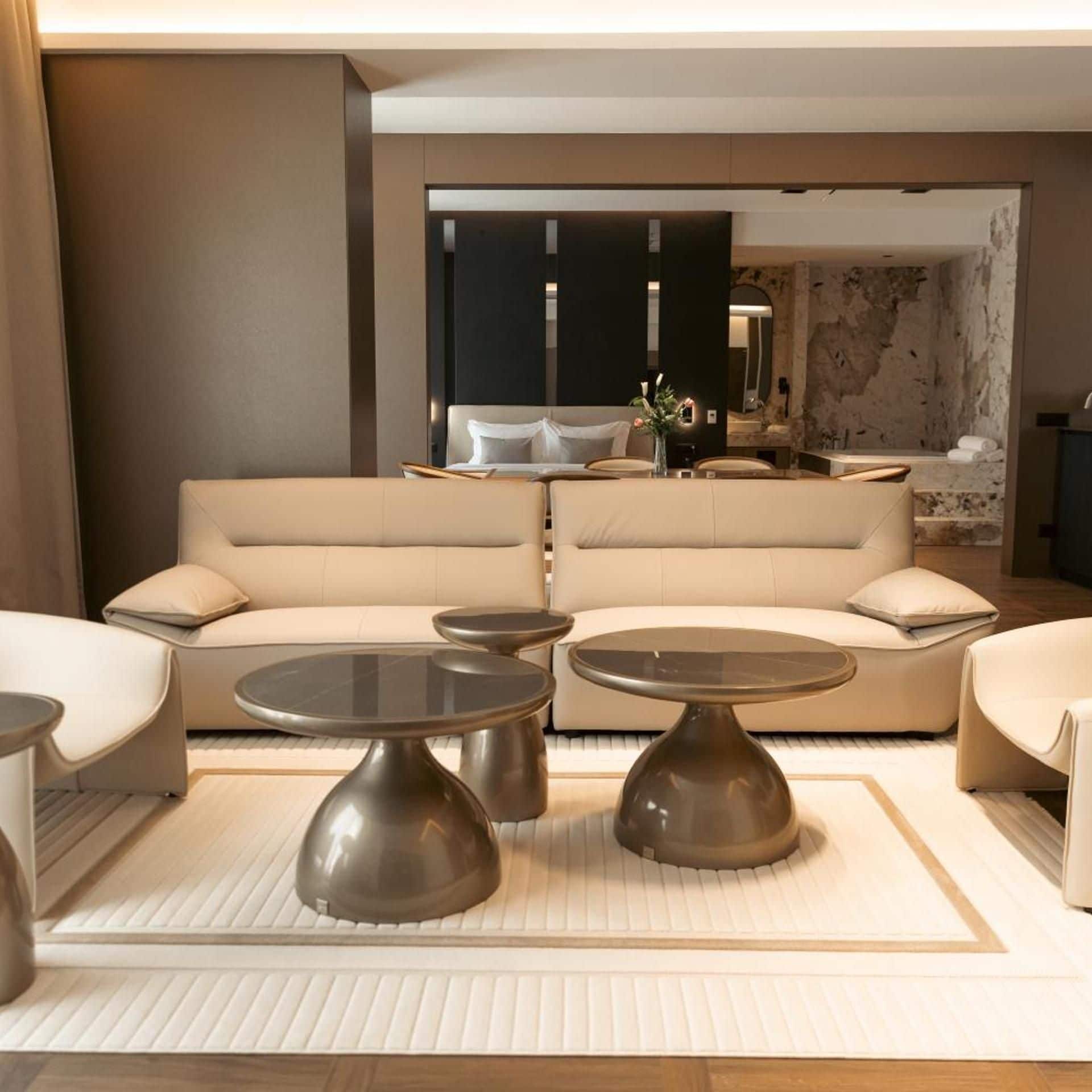 A modern living room with a sofa set, two round tables, and a decorative vase.