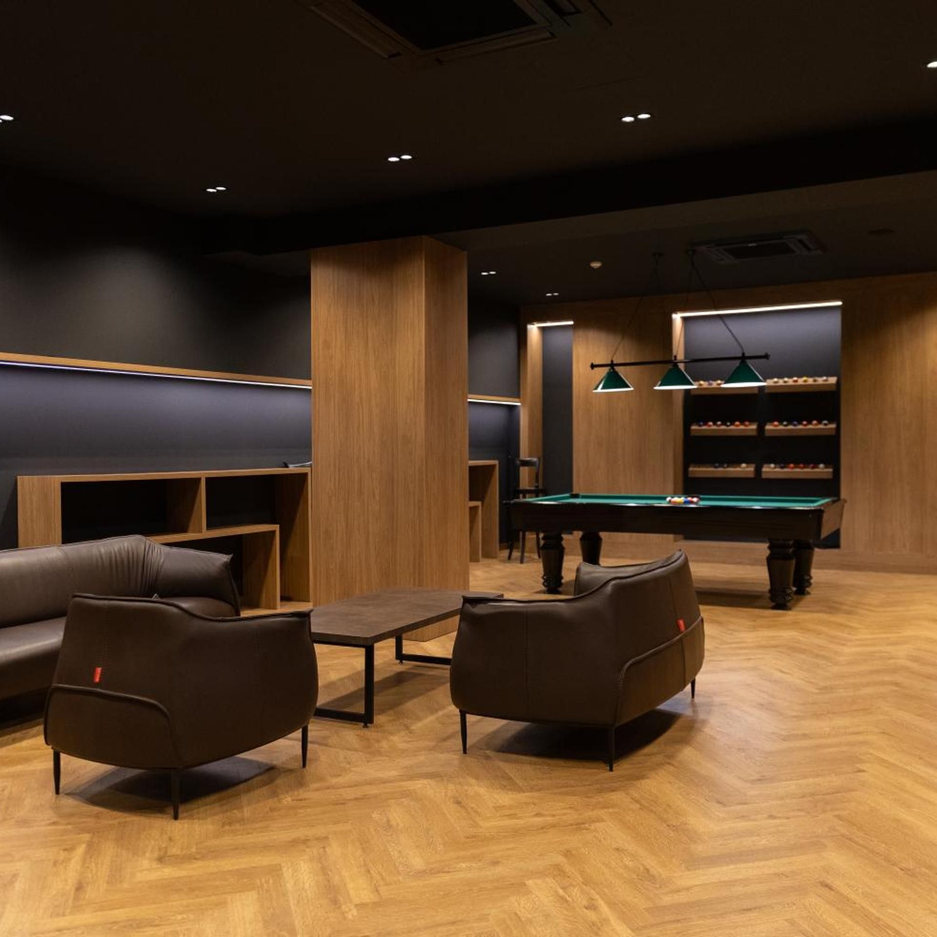 Une salle de billard équipée d’une table de billard, de deux canapés et d’une petite table.