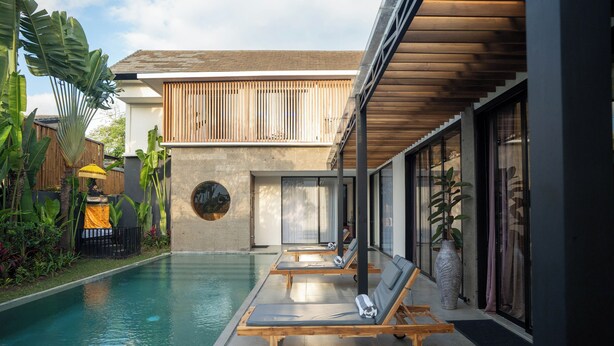 A modern pool area with lounge chairs, a concrete pool, and a wooden deck. - VILLA NANDI (Kerobokan)