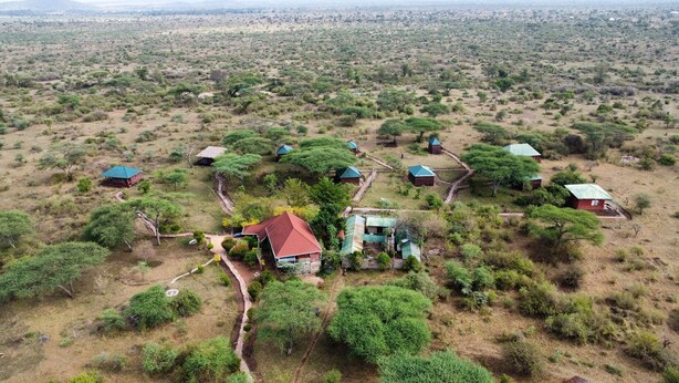 Une zone rurale où les maisons sont dispersées, certaines ayant des toits verts, et où la végétation est clairsemée, avec quelques arbres.