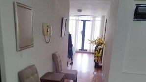 Un soggiorno spazioso con pavimento in legno, un divano beige, un tavolino e una pianta in vaso.