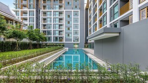 Un edificio moderno con piscina, rodeado de vegetación y un jardín cuidado.