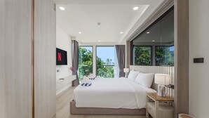 Una habitación de hotel moderna con una cama grande, un televisor montado en la pared y un balcón con vistas a la vegetación.