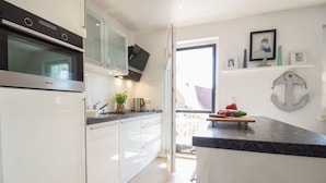 Een moderne keuken met witte kastjes, een roestvrijstalen oven en een flatscreen televisie boven de aanrecht.